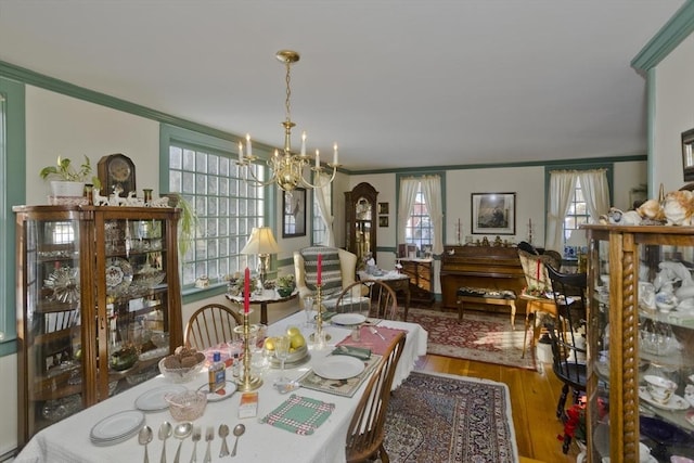 dining space with crown molding, a notable chandelier, and hardwood / wood-style flooring