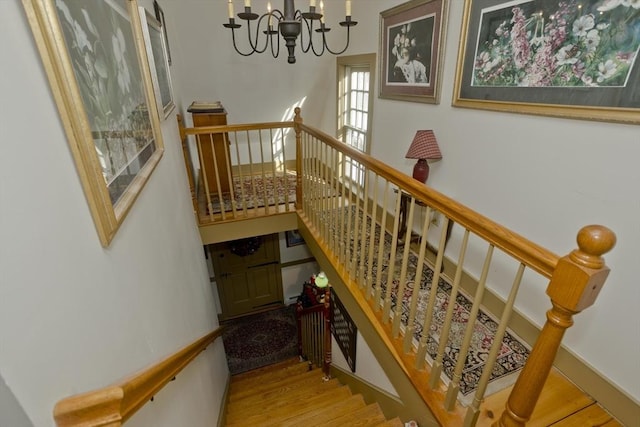 staircase featuring hardwood / wood-style flooring and a notable chandelier