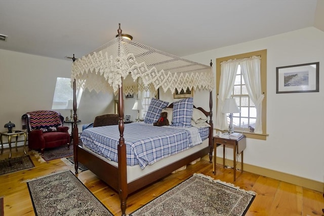 bedroom with a notable chandelier, hardwood / wood-style floors, and a baseboard heating unit