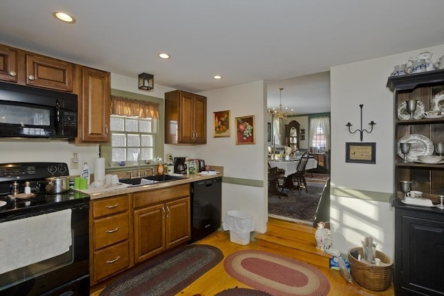 kitchen with a wealth of natural light, sink, hardwood / wood-style floors, and black appliances