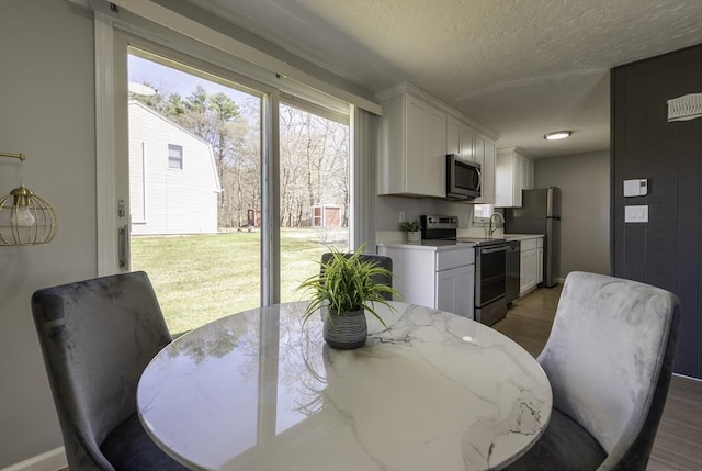 dining area featuring baseboards, a textured ceiling, and light wood finished floors