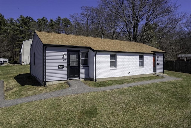 exterior space featuring brick siding, a shingled roof, and a front lawn