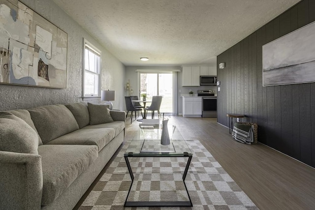 living room with wood walls, light wood finished floors, and a textured ceiling