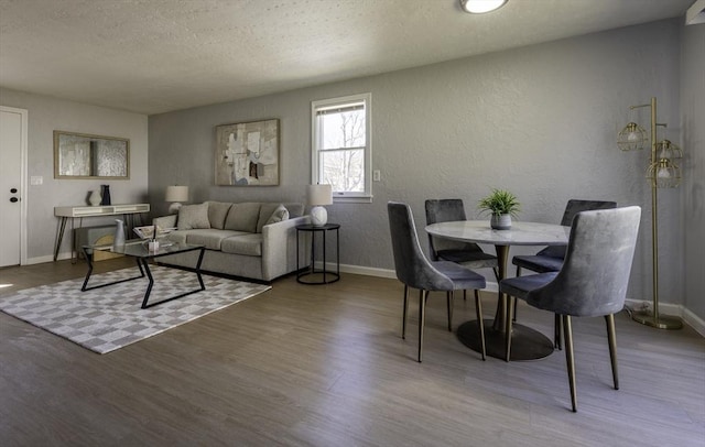 living area with baseboards, a textured wall, a textured ceiling, and wood finished floors