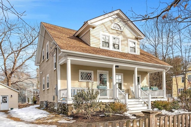 view of front facade featuring a porch, a shingled roof, and fence