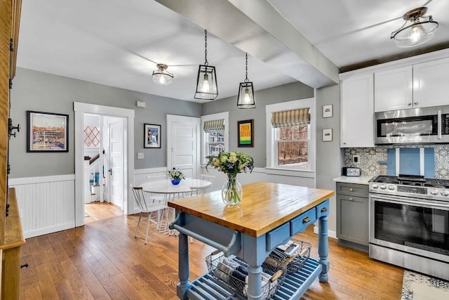 kitchen featuring butcher block countertops, a wainscoted wall, appliances with stainless steel finishes, and hardwood / wood-style floors