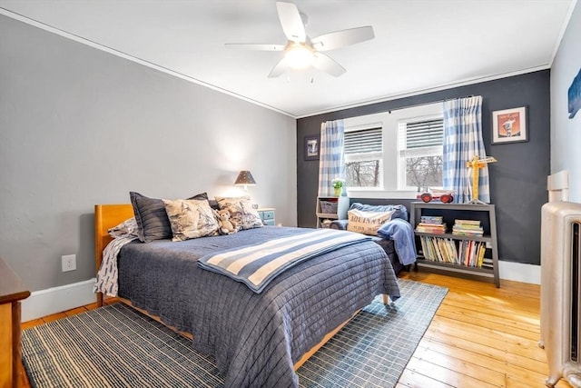 bedroom featuring ornamental molding, a ceiling fan, baseboards, and hardwood / wood-style flooring