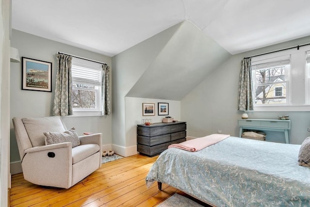 bedroom featuring hardwood / wood-style flooring, baseboards, and vaulted ceiling