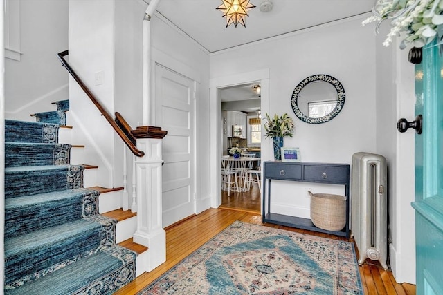 entryway with stairway, radiator heating unit, and wood finished floors