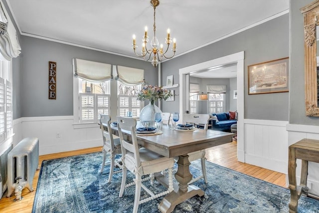 dining area featuring ornamental molding, radiator, wood finished floors, and wainscoting