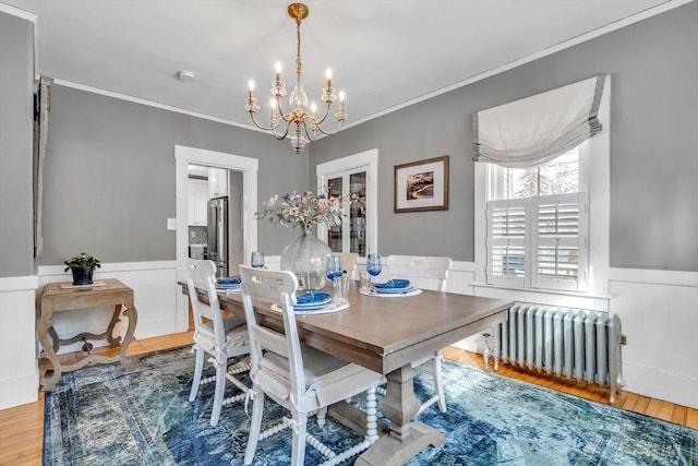 dining room with a wainscoted wall, crown molding, radiator heating unit, and wood finished floors