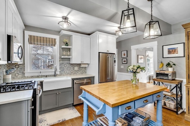 kitchen with wooden counters, open shelves, a sink, stainless steel appliances, and white cabinetry