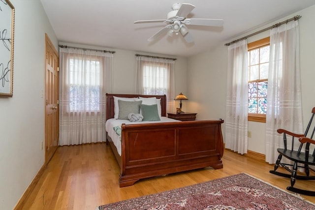 bedroom featuring ceiling fan, multiple windows, and light hardwood / wood-style floors