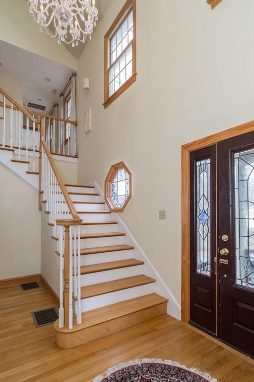 foyer featuring a chandelier, a towering ceiling, and hardwood / wood-style flooring