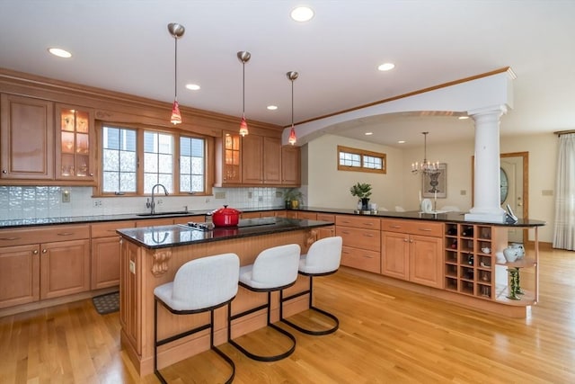 kitchen with decorative light fixtures, kitchen peninsula, sink, light hardwood / wood-style flooring, and a breakfast bar area