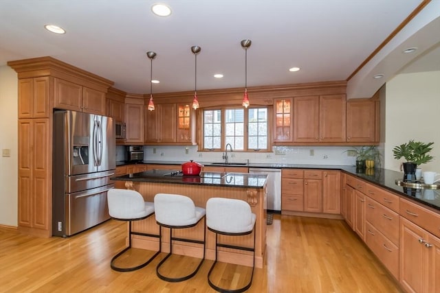 kitchen with a kitchen breakfast bar, appliances with stainless steel finishes, light hardwood / wood-style flooring, and a kitchen island