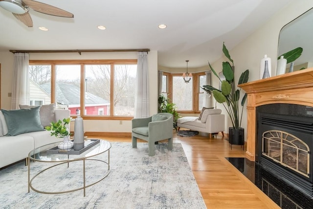 living room with ceiling fan with notable chandelier and hardwood / wood-style flooring