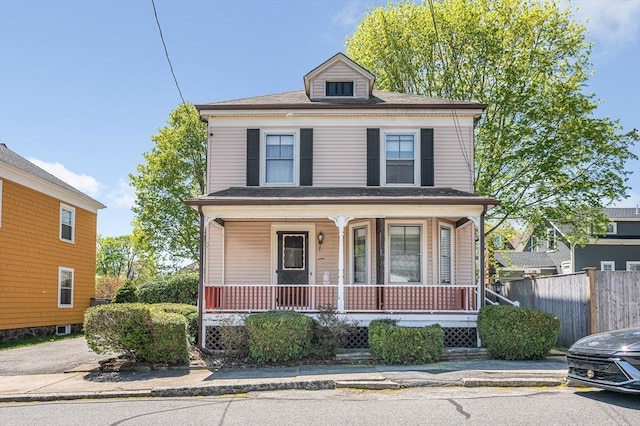 american foursquare style home with a porch and fence