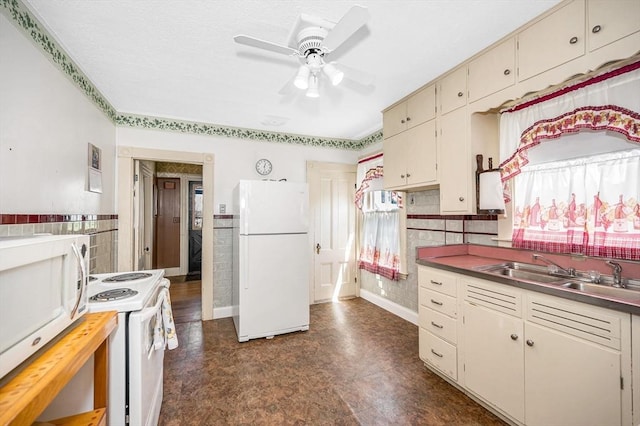 kitchen featuring ceiling fan, a sink, white appliances, a wainscoted wall, and cream cabinetry