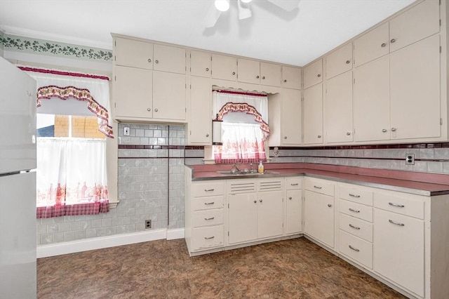 kitchen with freestanding refrigerator, a ceiling fan, dark floors, and a sink