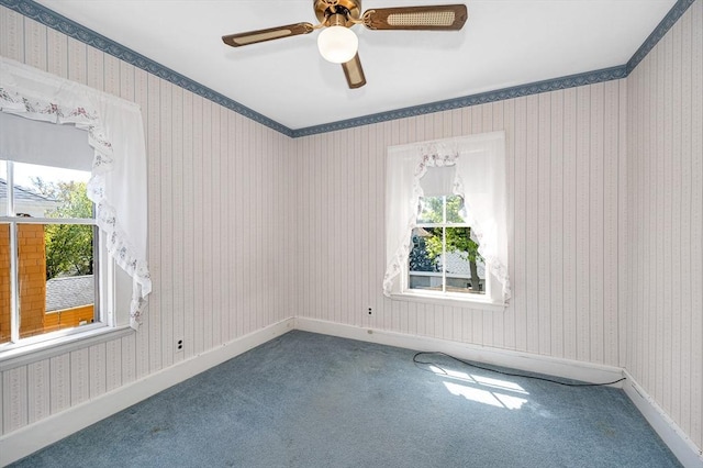 carpeted spare room featuring baseboards, ceiling fan, wallpapered walls, and a wealth of natural light