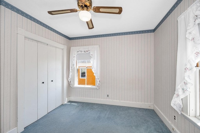 unfurnished bedroom featuring carpet floors, wallpapered walls, ceiling fan, and a closet