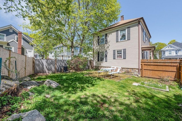 back of property with a lawn, a fenced backyard, and a chimney