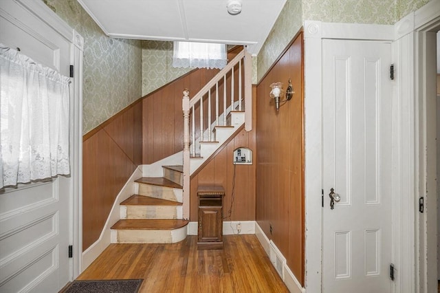 staircase with visible vents, wood finished floors, and wallpapered walls