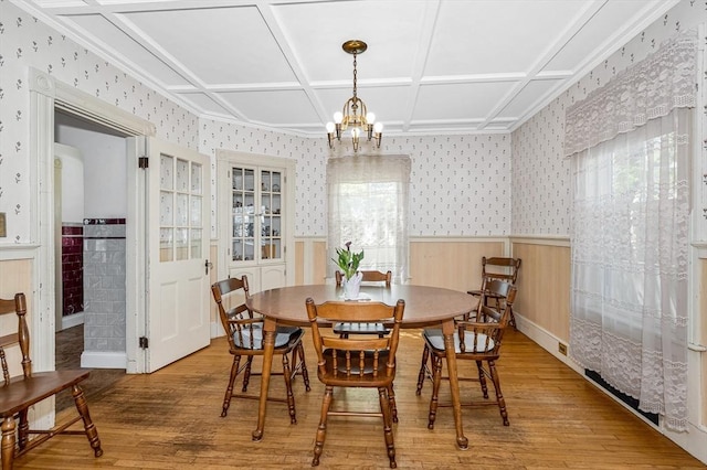 dining space with a wainscoted wall, a healthy amount of sunlight, hardwood / wood-style flooring, and wallpapered walls