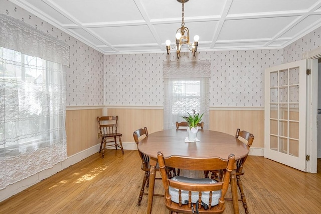 dining space with wood-type flooring, wainscoting, a chandelier, and coffered ceiling