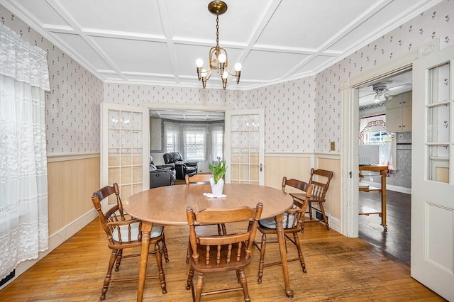 dining space featuring wood-type flooring, wainscoting, wallpapered walls, and plenty of natural light