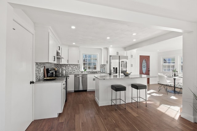 kitchen featuring white cabinets, a wealth of natural light, a kitchen island, dark hardwood / wood-style flooring, and stainless steel appliances