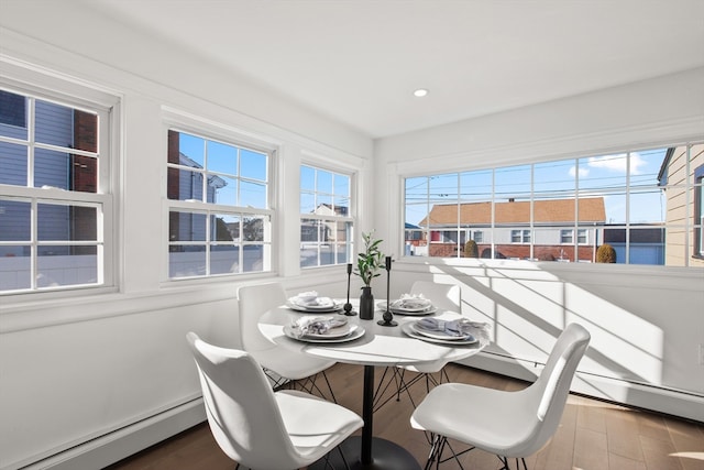 dining space with hardwood / wood-style floors and a baseboard heating unit