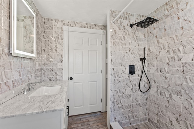 bathroom with tiled shower, vanity, tile walls, and hardwood / wood-style flooring