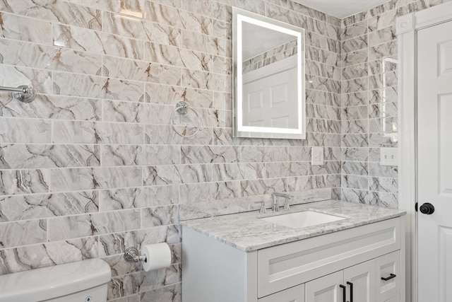 bathroom with vanity, tile walls, and toilet