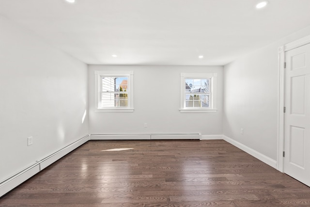 spare room featuring a wealth of natural light, dark hardwood / wood-style flooring, and a baseboard heating unit