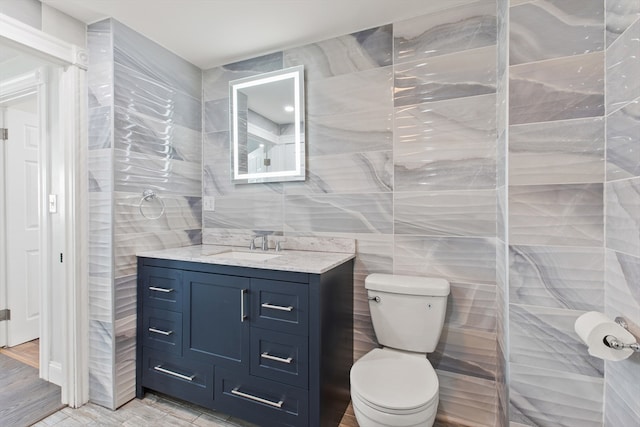 bathroom featuring hardwood / wood-style floors, vanity, tile walls, and toilet