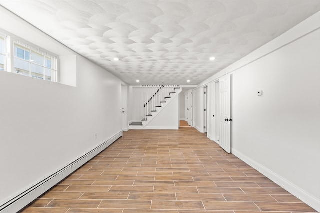 basement featuring light hardwood / wood-style floors and a baseboard heating unit