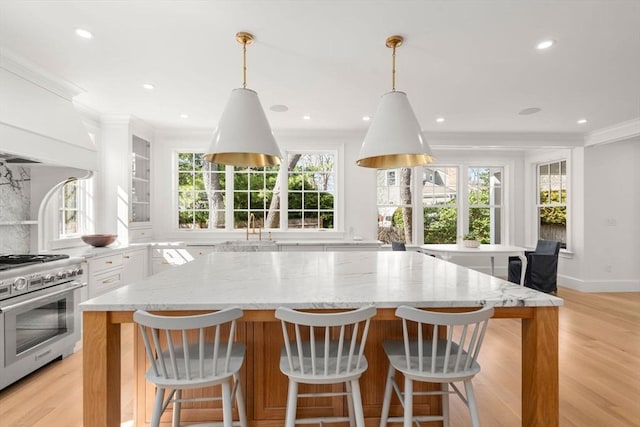32 S Woodside Ave, Wellesley, MA 02482 - kitchen featuring high end range, a kitchen island, white cabinetry, light wood-style flooring, and ornamental molding