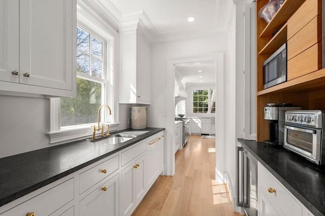 32 S Woodside Ave, Wellesley, MA 02482 - kitchen with ornamental molding, a sink, dark countertops, light wood-style floors, and white cabinets