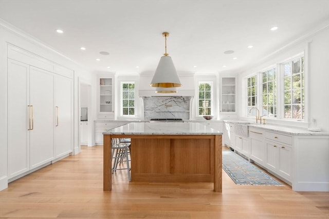 32 S Woodside Ave, Wellesley, MA 02482 - kitchen with a sink, crown molding, light wood-style floors, a kitchen island, and white cabinetry
