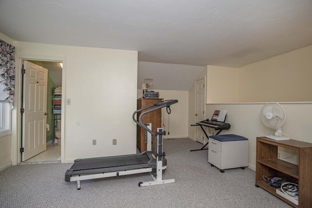 exercise room with vaulted ceiling and light carpet