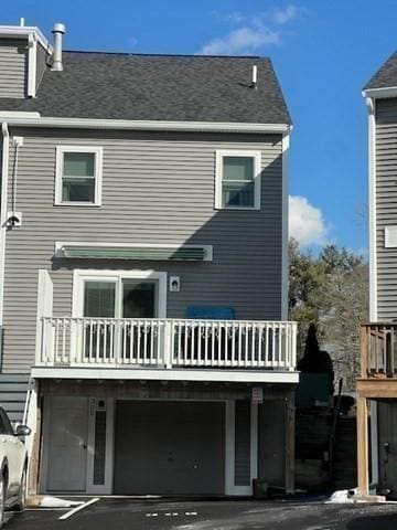 rear view of property featuring a garage and a balcony