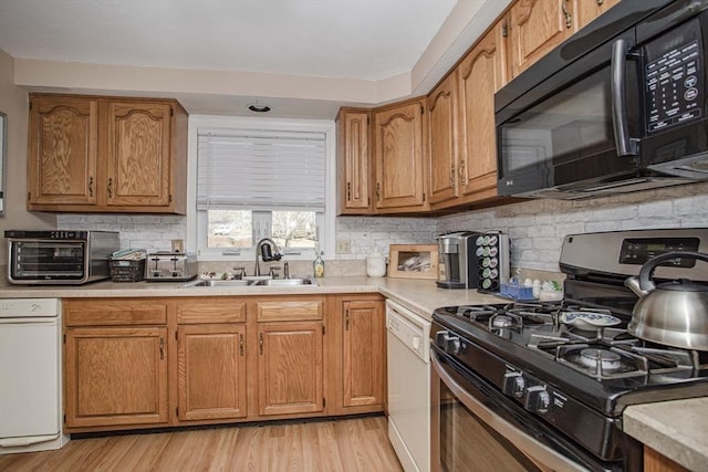 kitchen featuring sink, stainless steel gas stove, tasteful backsplash, light wood-type flooring, and dishwasher