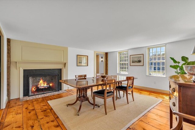 dining area with a fireplace with flush hearth and light wood-style floors