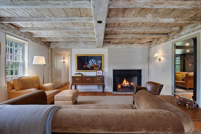 living area with a fireplace with flush hearth, wooden ceiling, beamed ceiling, and wood finished floors