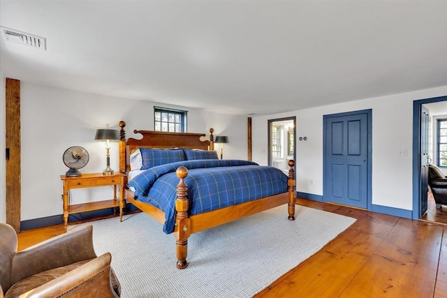 bedroom featuring visible vents, baseboards, and wood finished floors