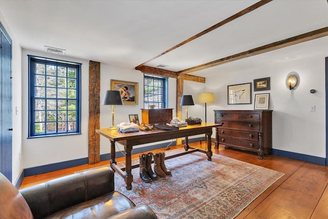 office space with baseboards, a wealth of natural light, wood finished floors, and visible vents