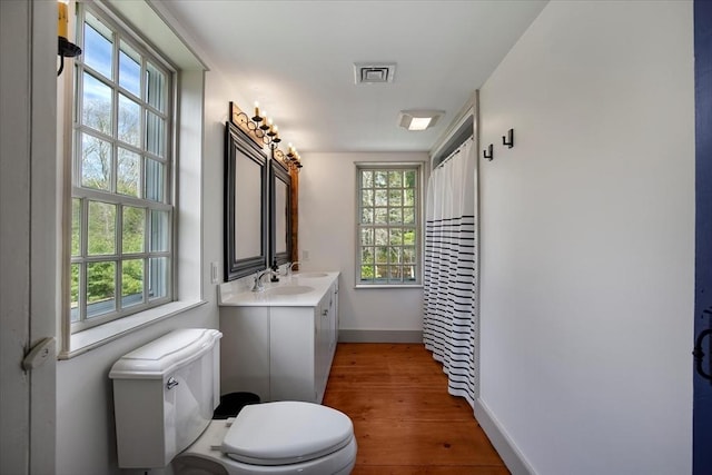 bathroom featuring plenty of natural light, baseboards, wood finished floors, and toilet