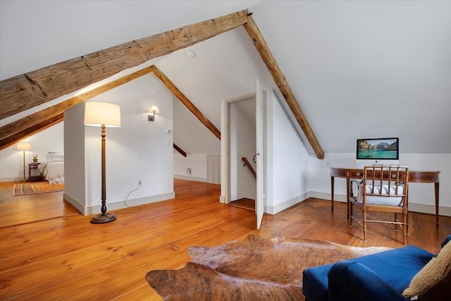 additional living space with baseboards, lofted ceiling with beams, and hardwood / wood-style flooring